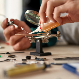 επισκευή πολύ μικρού αντικειμένου με τη βοήθεια μεγεθυντικού φακού και ειδικής κόλλας επισκευών